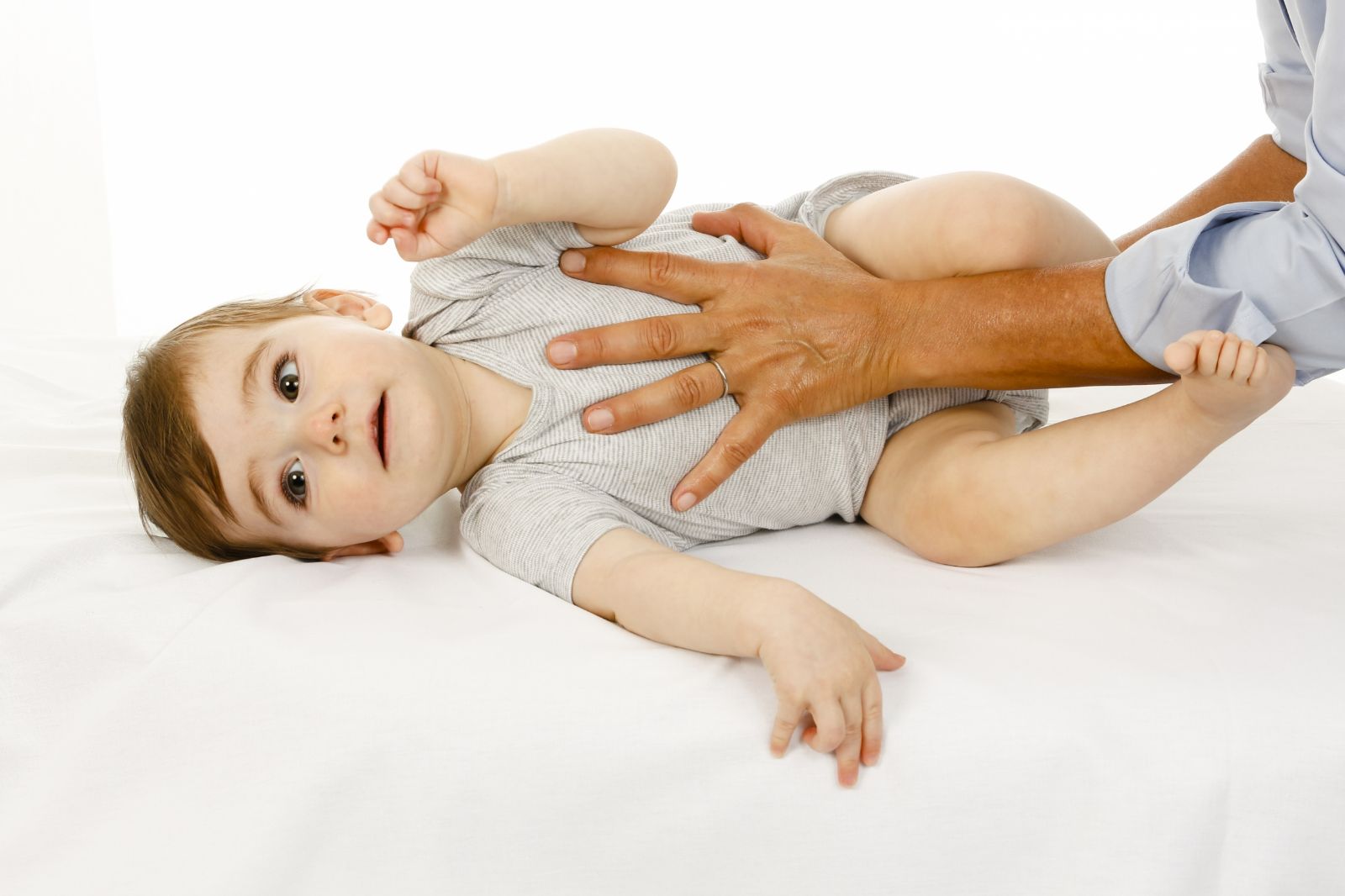 Osteopathische Behandlung eines Babys: eine Hand liegt sanft auf Brust und Bauch des liegenden Kindes